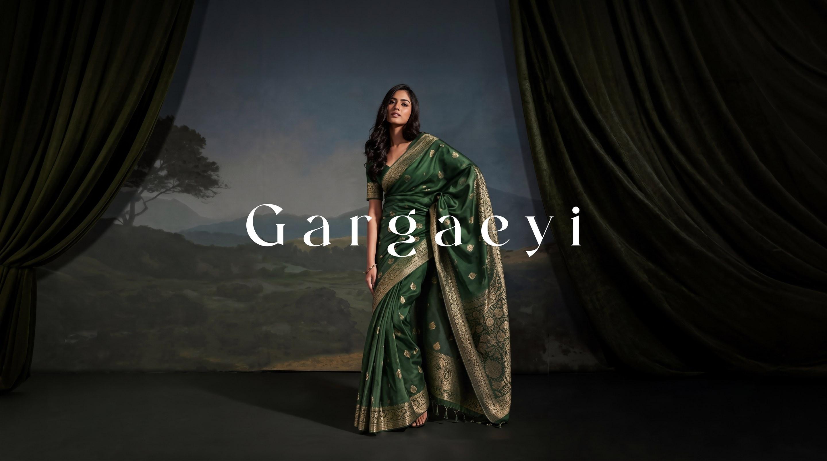 Gargaeyi — emerald silk saree with woven zari border, on a painted-landscape stage